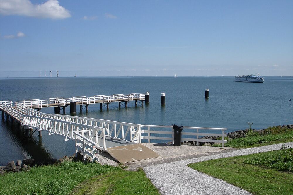 Witte houten steiger aan het IJsselmeer bij Medemblik met een rondvaartboot op het water