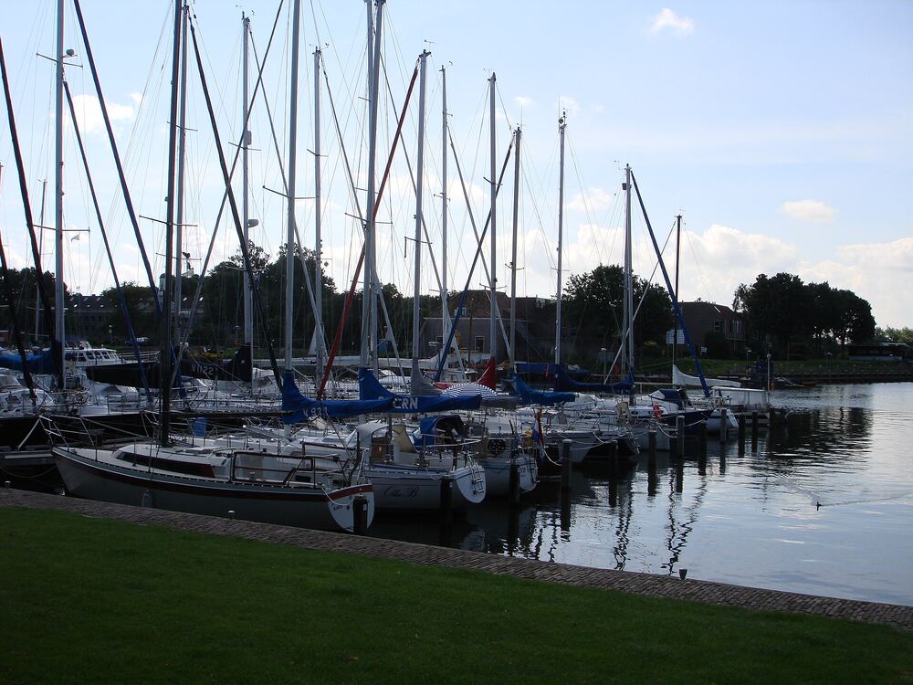 Zeilboten afgemeerd in de jachthaven van Medemblik, gezien vanaf het gras langs de kade